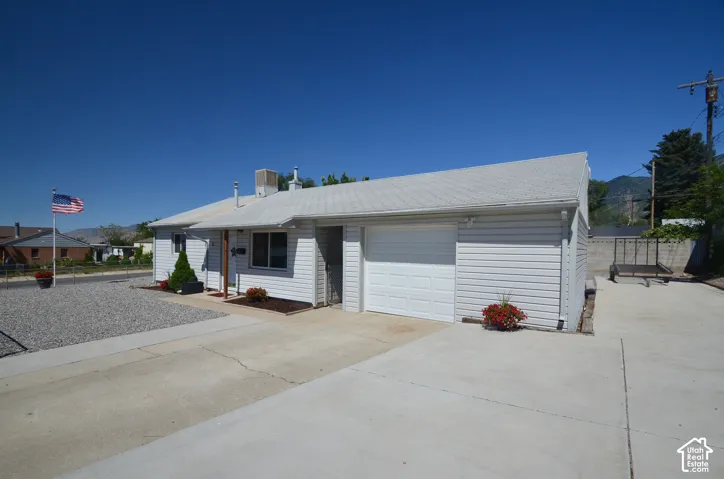 White siding exterior with an attached garage, concrete driveway, and gravel landscaping