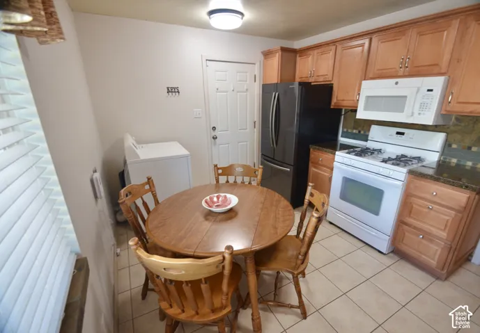 Kitchen featuring light wood cabinetry, dark speckled countertops, a mosaic tile backsplash, and tile flooring