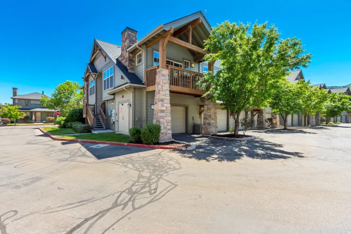Exterior featuring a stone and wood-frame facade, multiple garage doors, and an upper-level balcony with wood railings