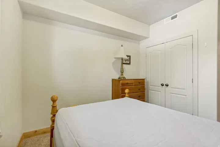 Room featuring neutral wall tones, carpeted flooring, white trim, and a double-door closet with arch paneling
