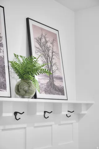 Built-in white paneling with integrated shelving and three black coat hooks