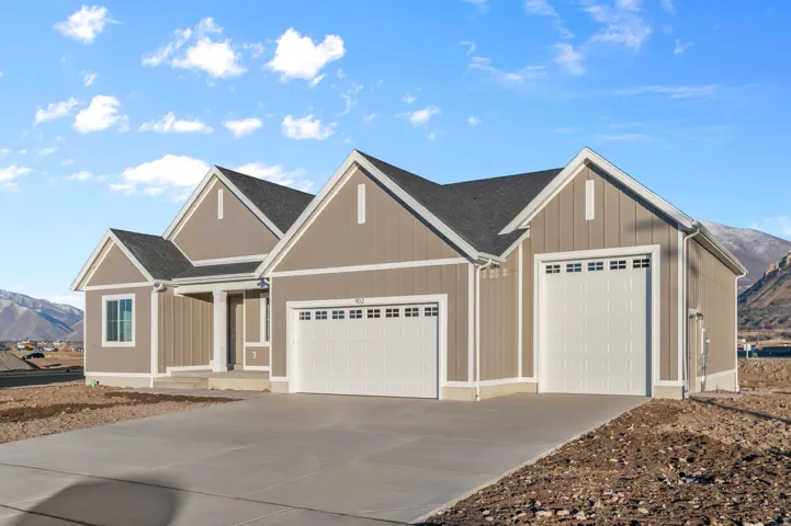 Contemporary ranch-style residence featuring a prominent two-car garage, neutral-toned vertical and horizontal siding, white trim accents, and a dark shingle roof