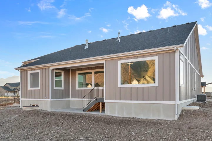 Rear exterior with covered patio featuring concrete flooring and black metal railings