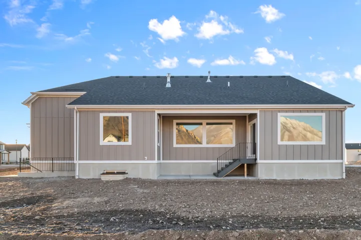 Rear exterior featuring a covered patio, dark gray shingle roof, and light tan siding