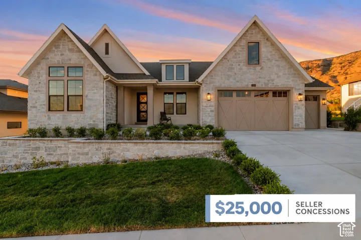 Stone facade exterior featuring high-pitched gables, multi-car garage with cross-buck carriage doors, masonry retaining wall, and mountain backdrop