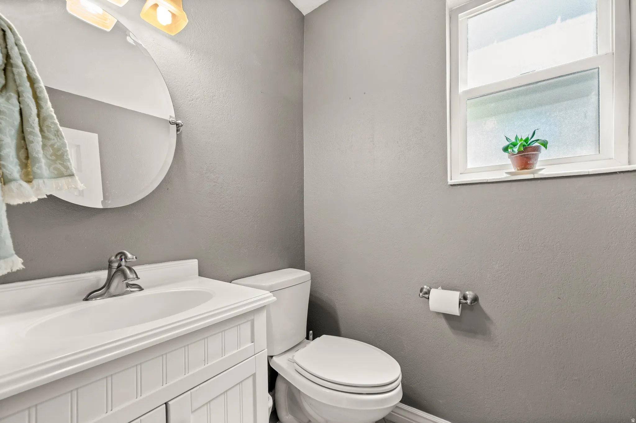 Bathroom featuring a white beadboard vanity, integrated sink, and brushed chrome faucet