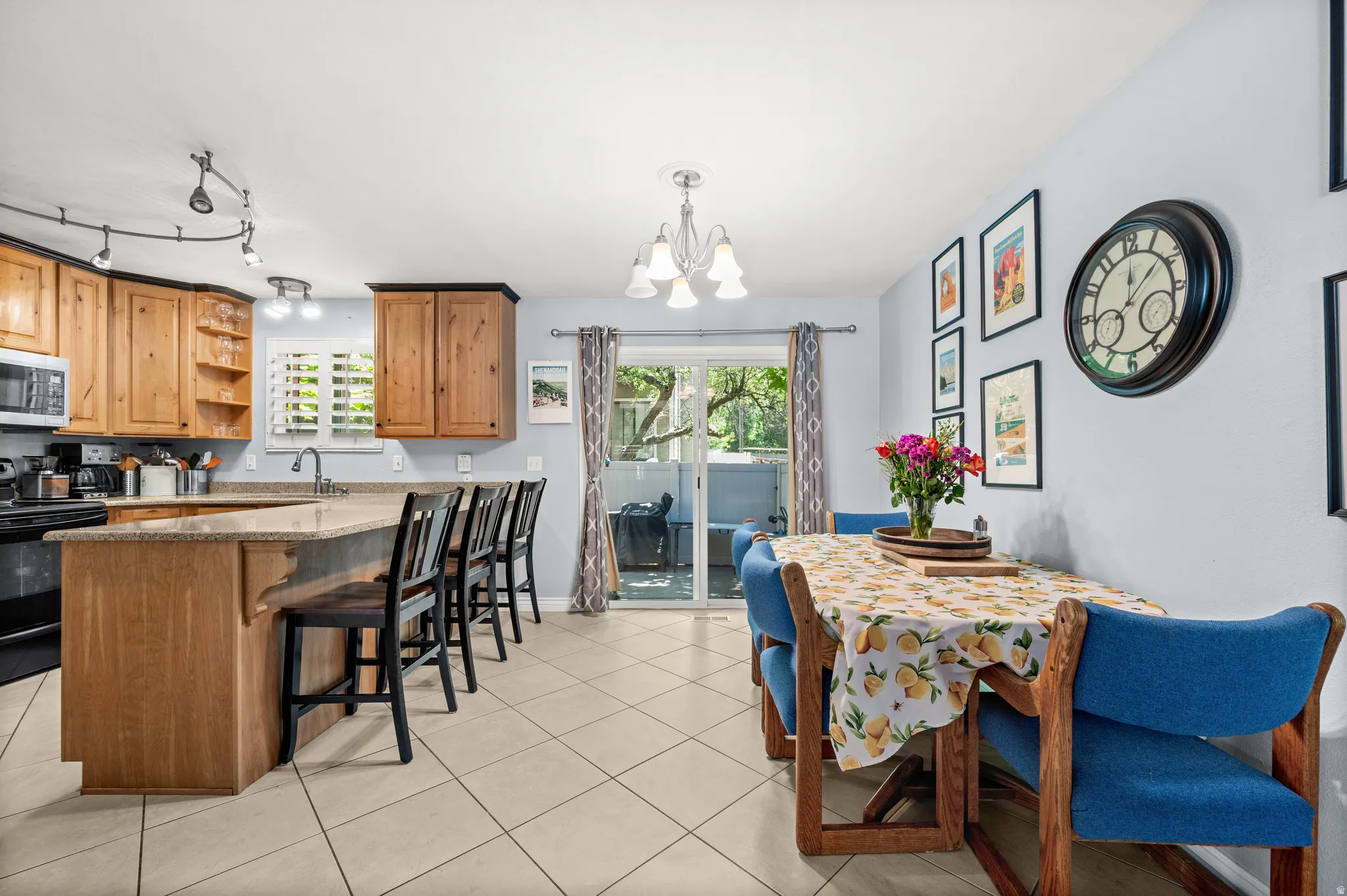 Kitchen and dining area featuring natural wood cabinetry, light-toned countertops, and tile flooring
