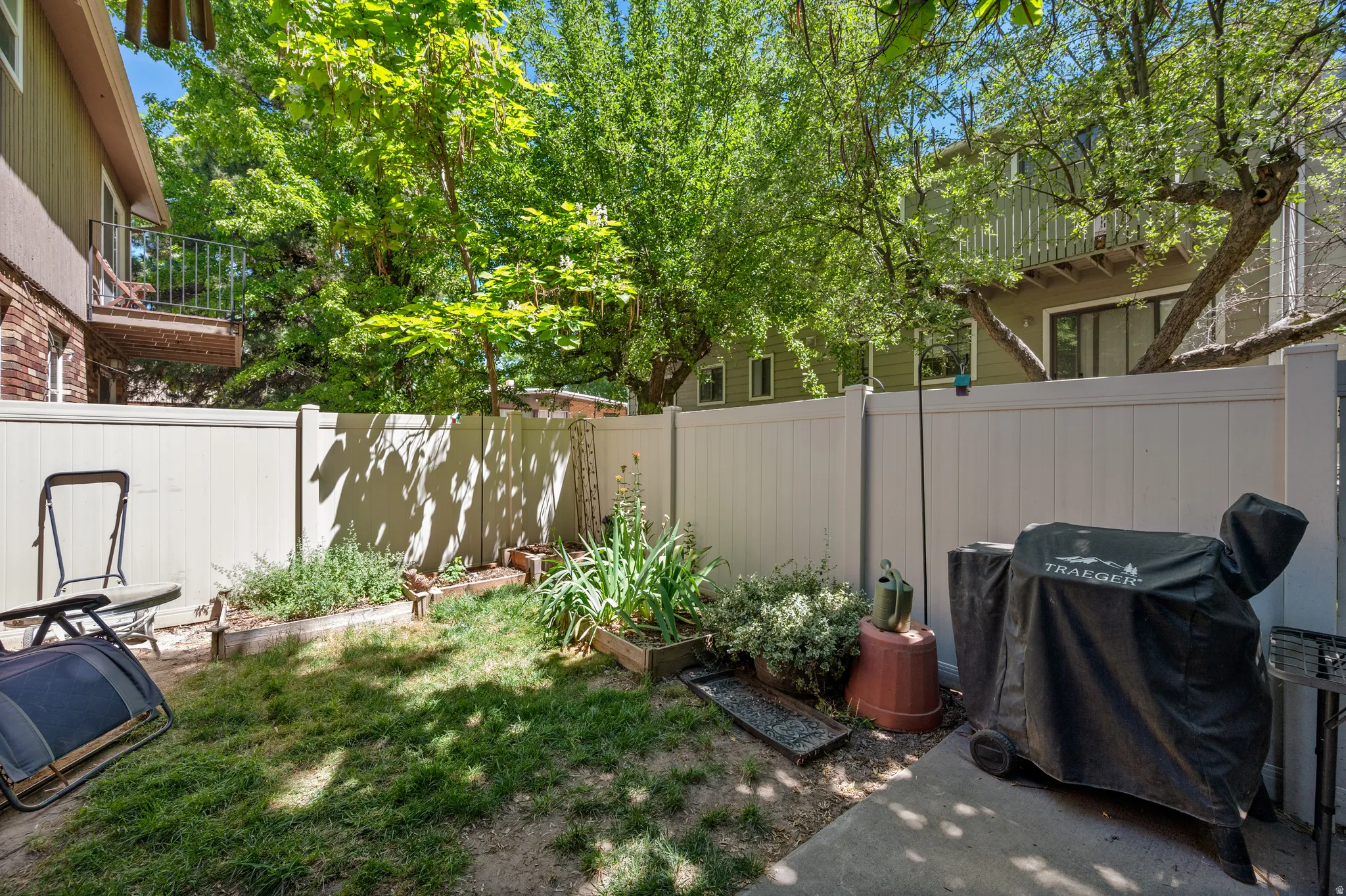 Private backyard space featuring a partial concrete patio, a section of lawn, and raised garden beds