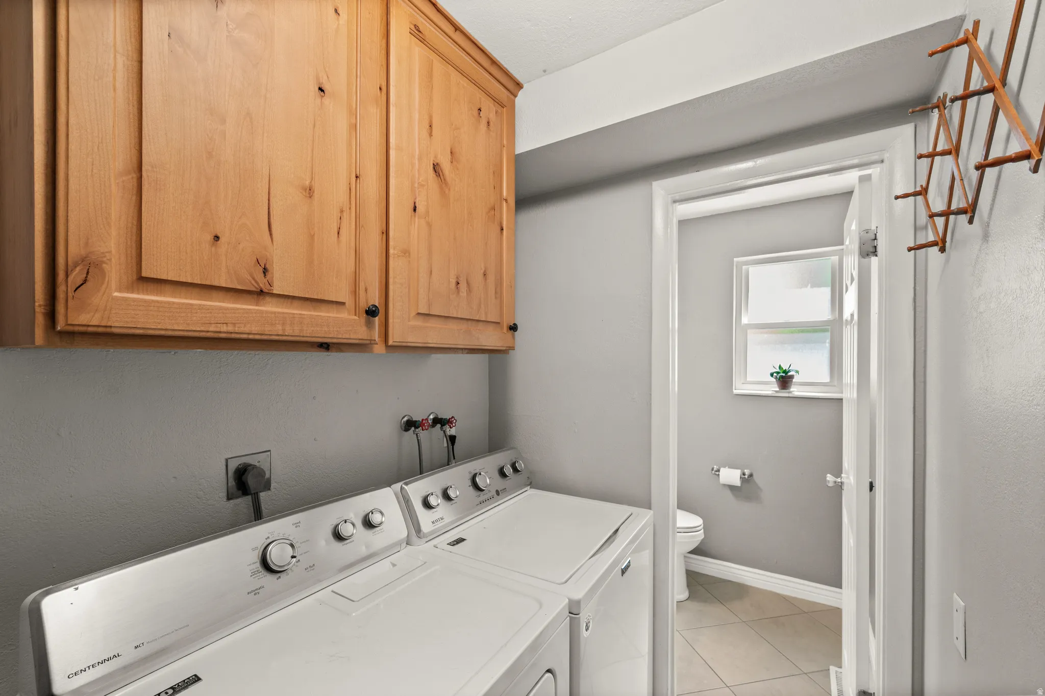 Laundry area featuring light wood cabinetry
