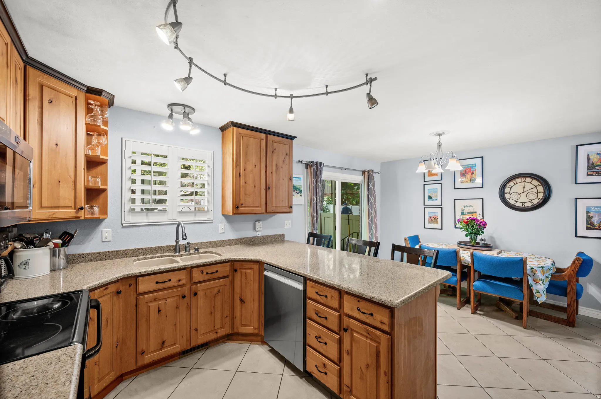 Kitchen and dining area featuring light wood cabinetry, stone-finish countertops, and a dual-basin sink