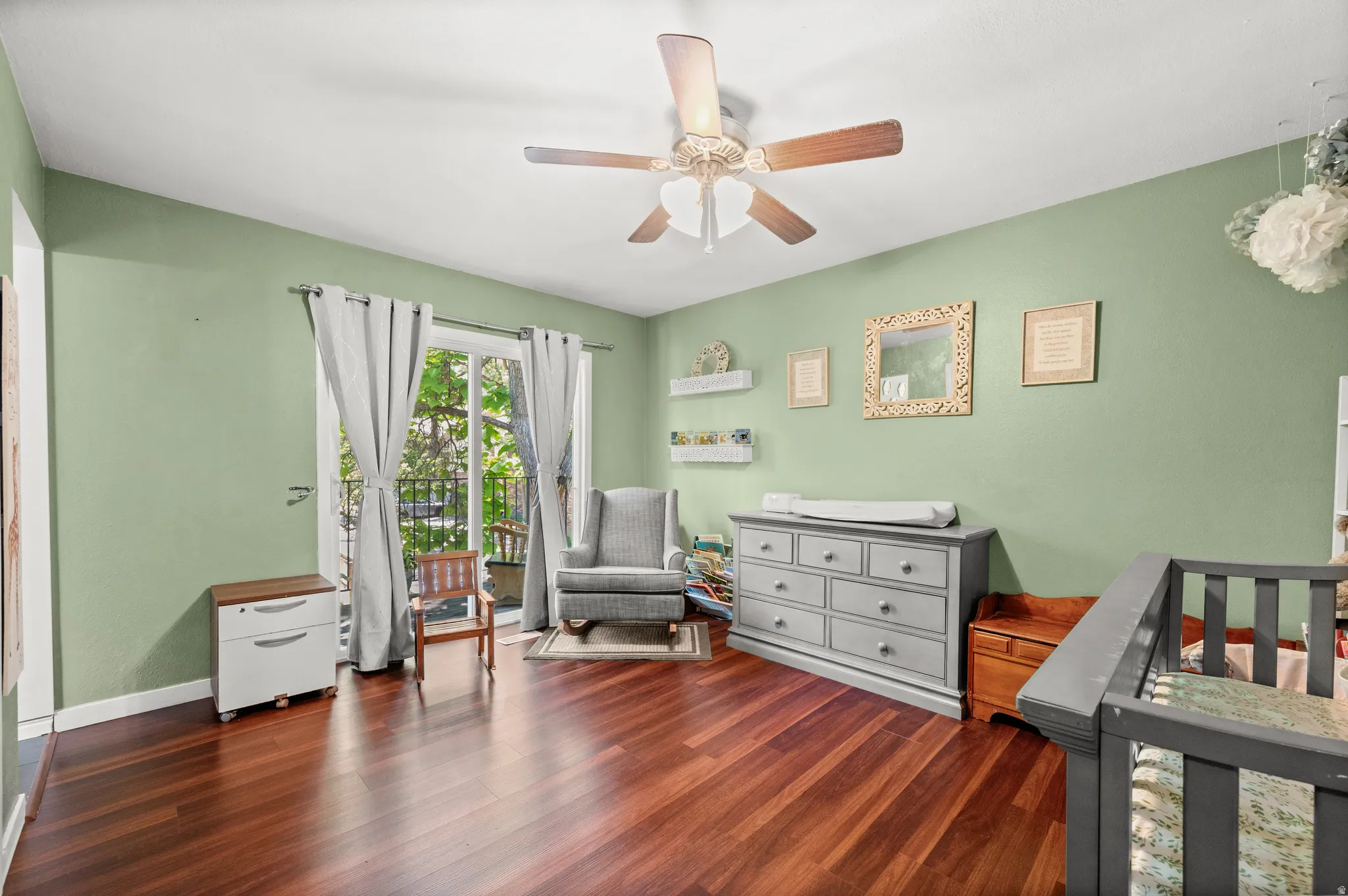 Spacious room featuring rich wood-finish flooring, a ceiling fan, and wall-mounted shelving