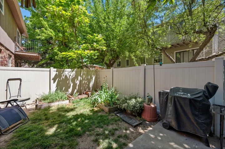 Private backyard space featuring a partial concrete patio, a section of lawn, and raised garden beds