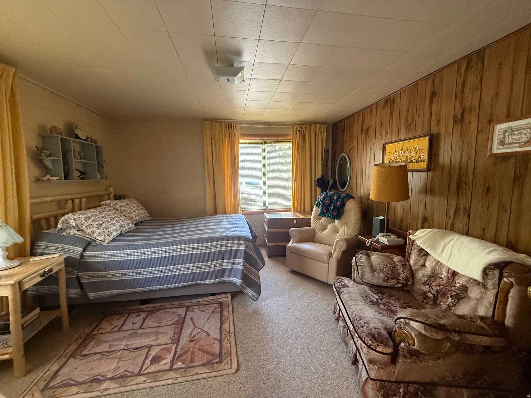 Bedroom featuring wood-panel accent wall and a window with natural light