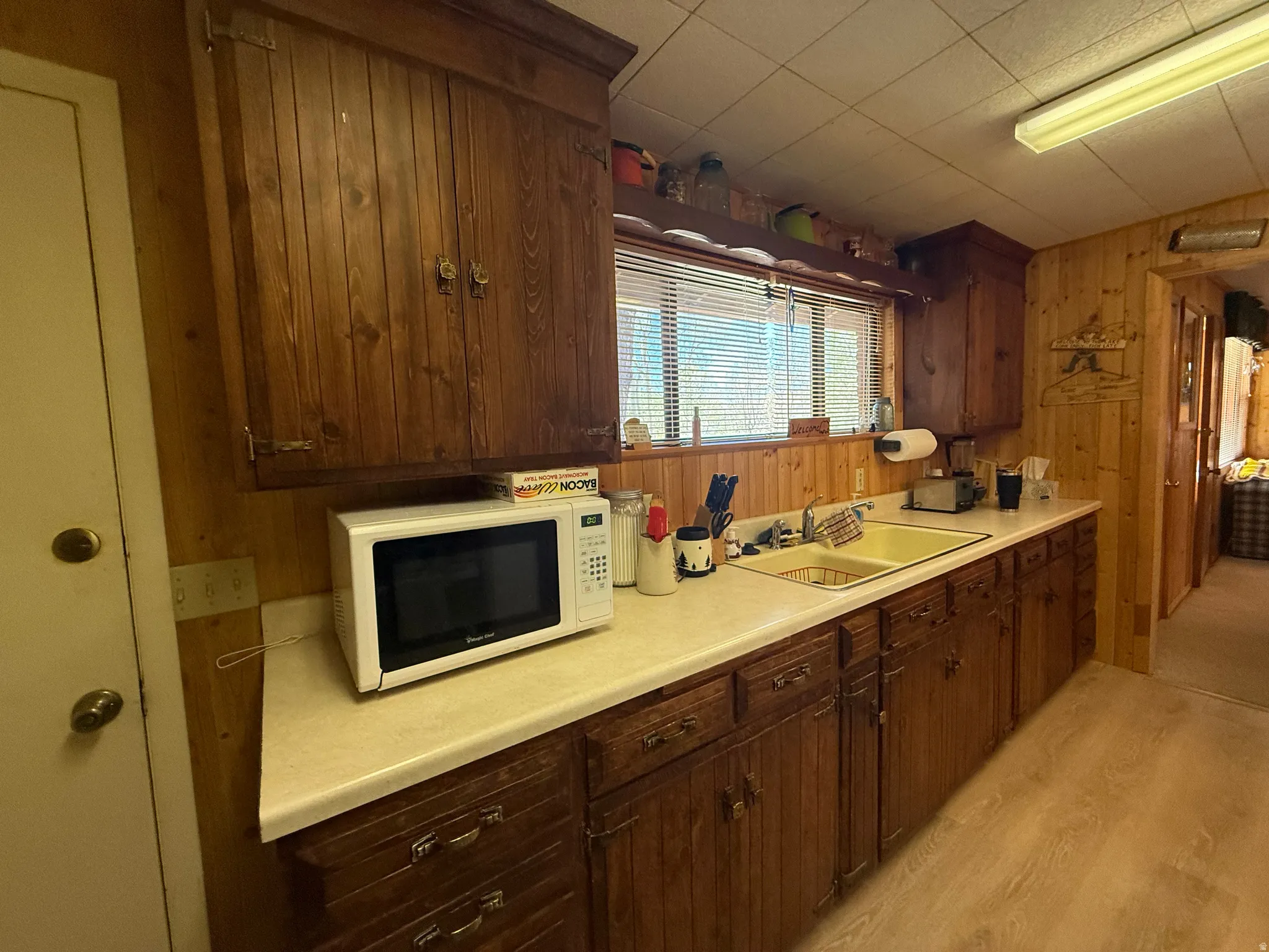 Kitchen featuring wood-finish cabinetry, light-toned countertops, and a double basin sink