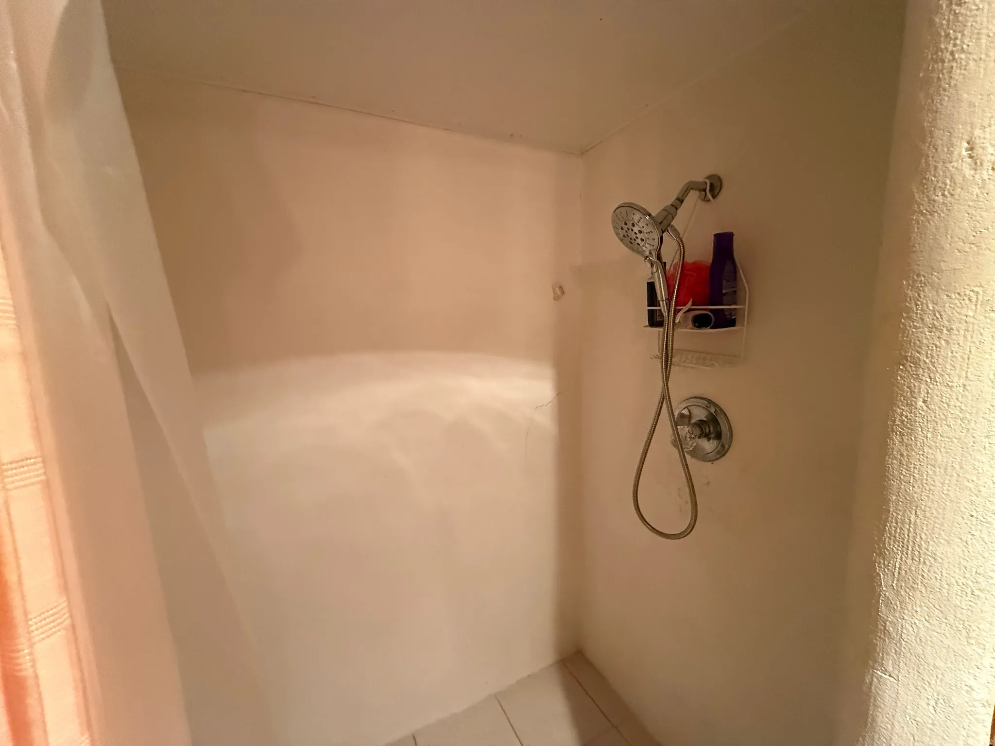 Shower area featuring a fixed and handheld showerhead combination with chrome fixtures