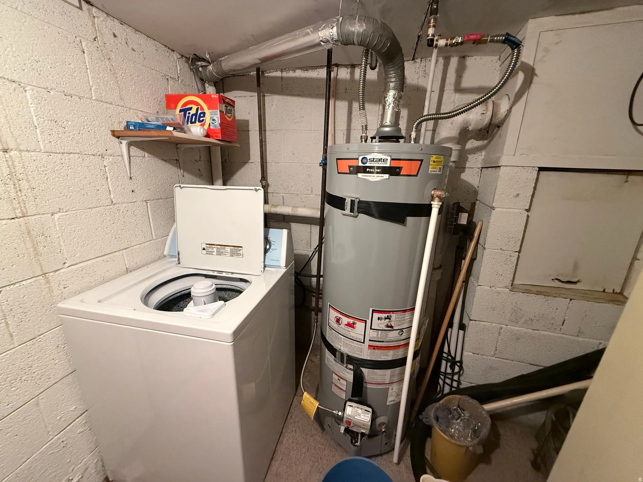 Dedicated utility area featuring a water heater, top-loading washing machine, and concrete block walls