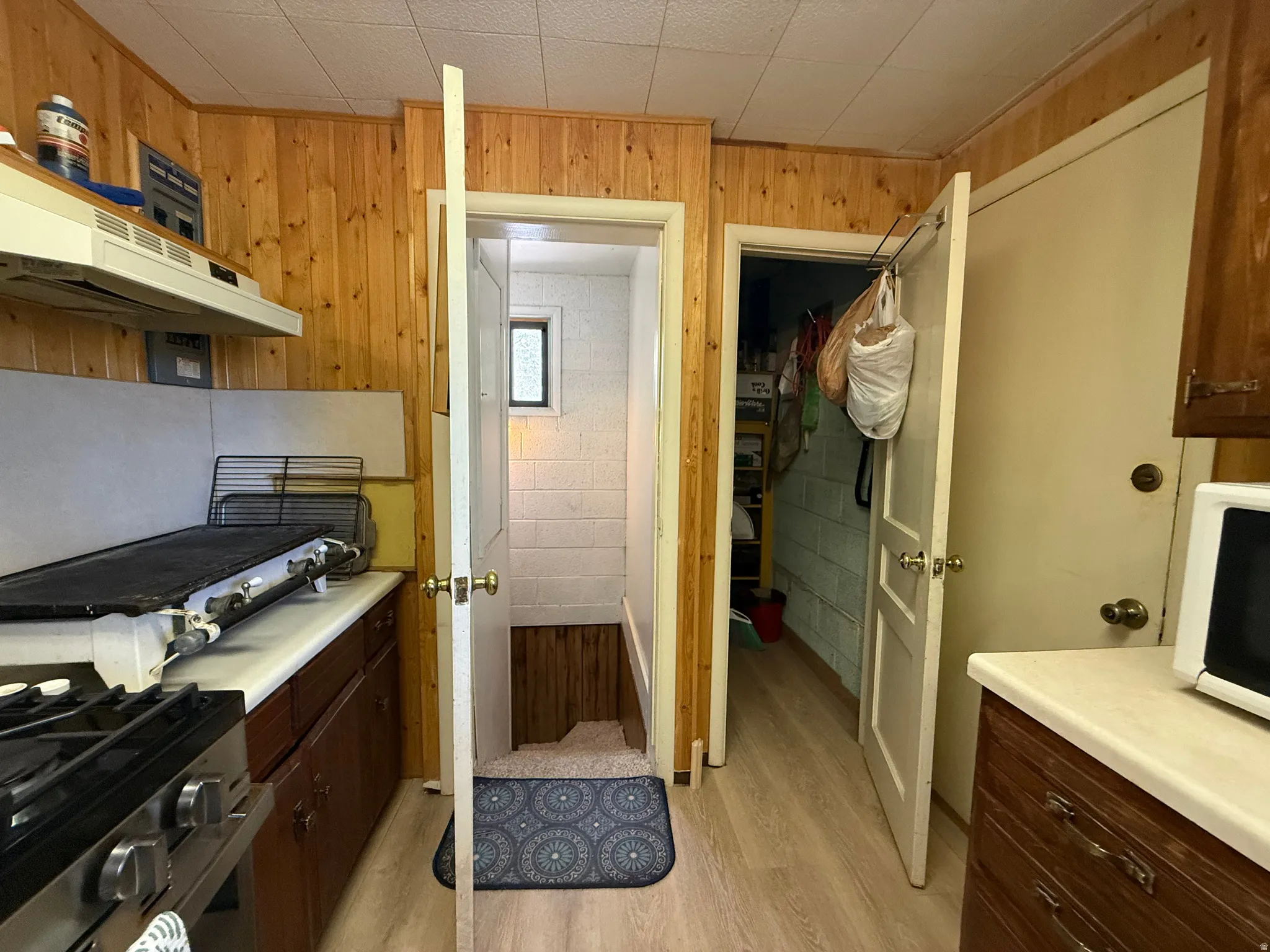 Kitchen area featuring wood-paneled walls and light wood-finish flooring
