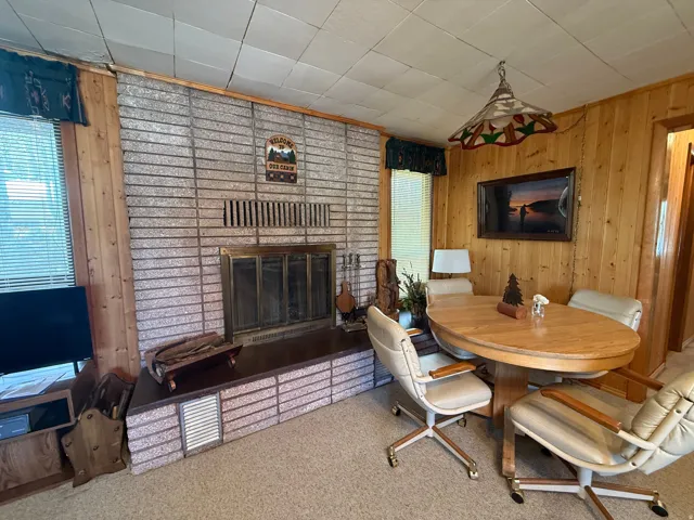Interior space featuring a brick fireplace with a metal insert, wood-paneled walls, and a tiled ceiling