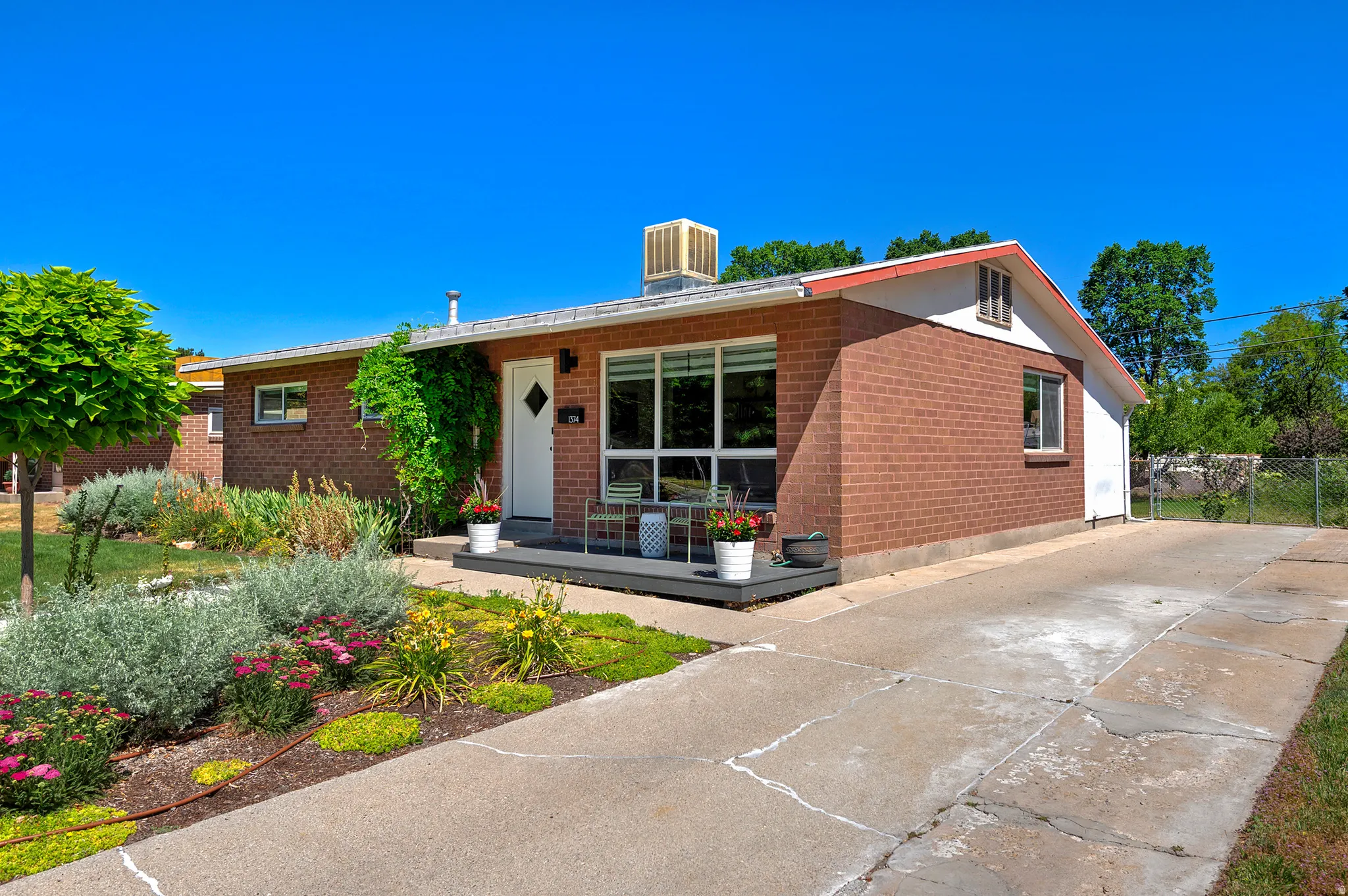 Brick facade residence featuring a front porch, expansive window, and established landscaping