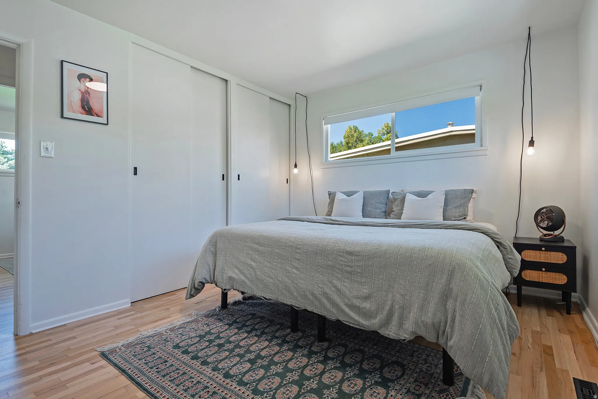 Hardwood flooring throughout, featuring a broad window, white sliding closet doors, and light-colored walls