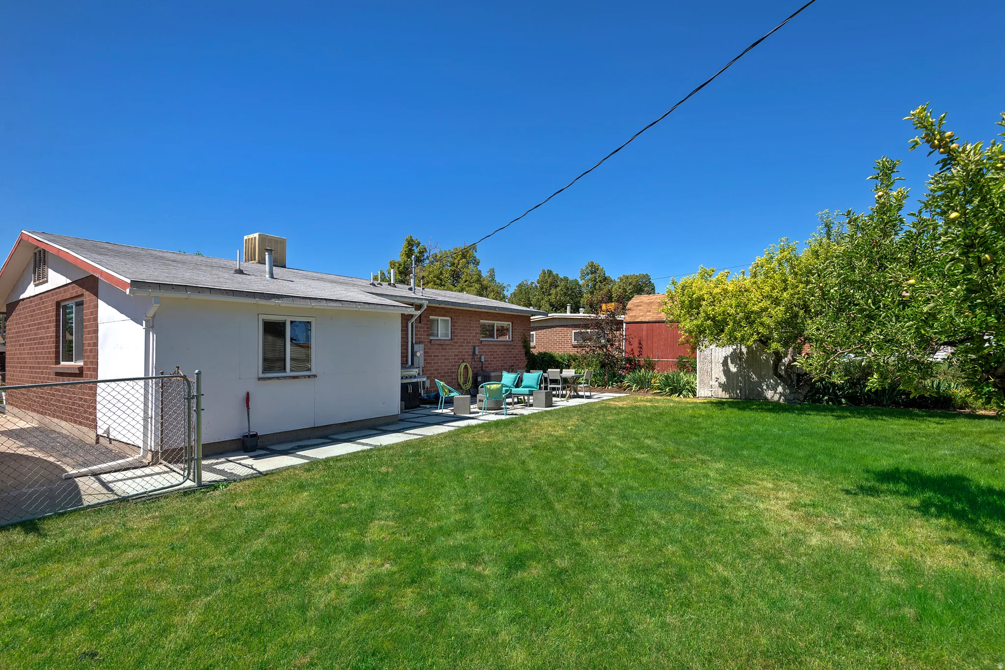 Expansive green lawn with mature trees and a paved patio area