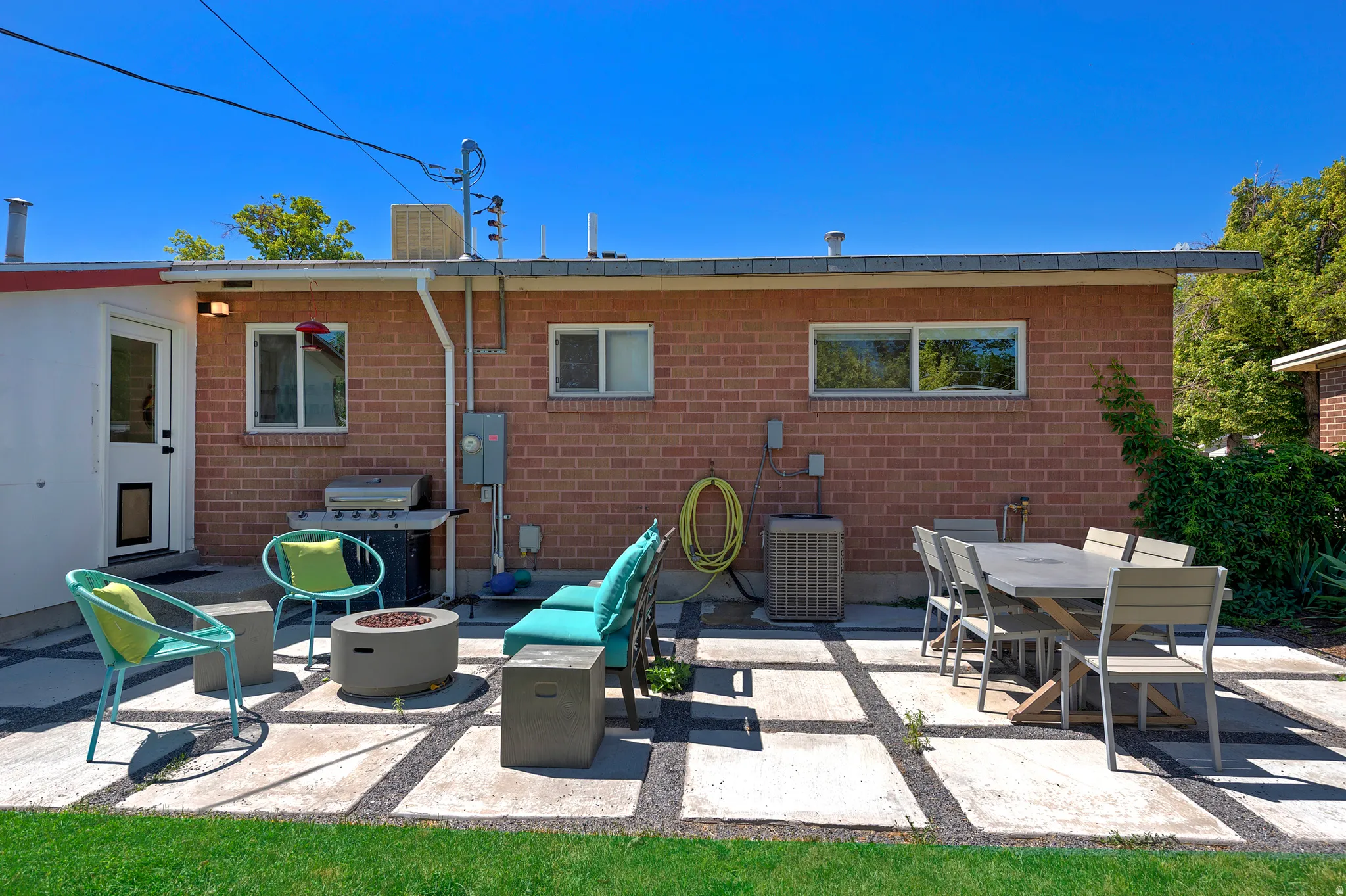 Backyard patio featuring concrete pavers with gravel fill, a red brick exterior, and a manicured lawn