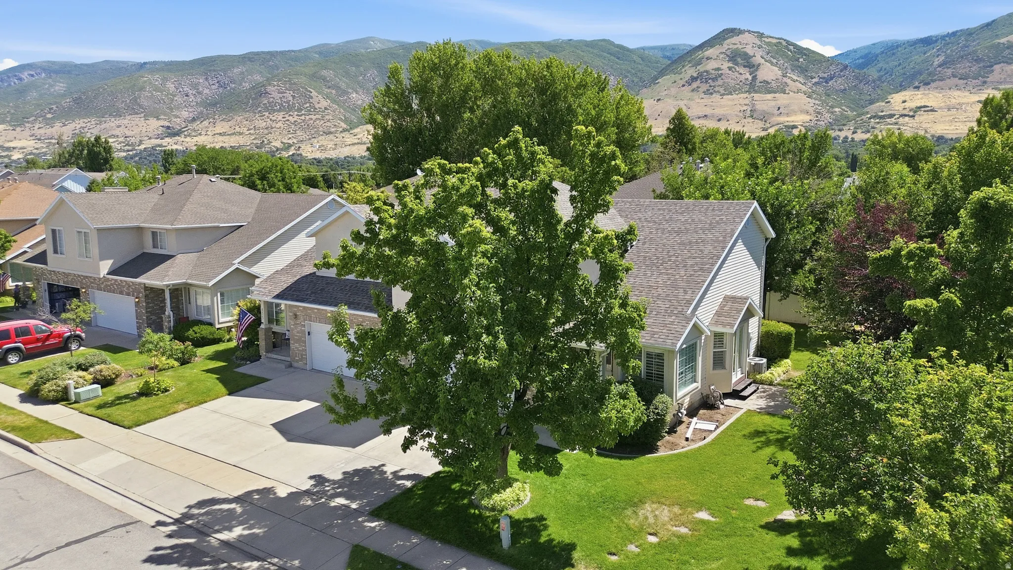 Traditional style residence featuring a light-toned exterior with stone accents, a multi-car driveway, and mature landscaping