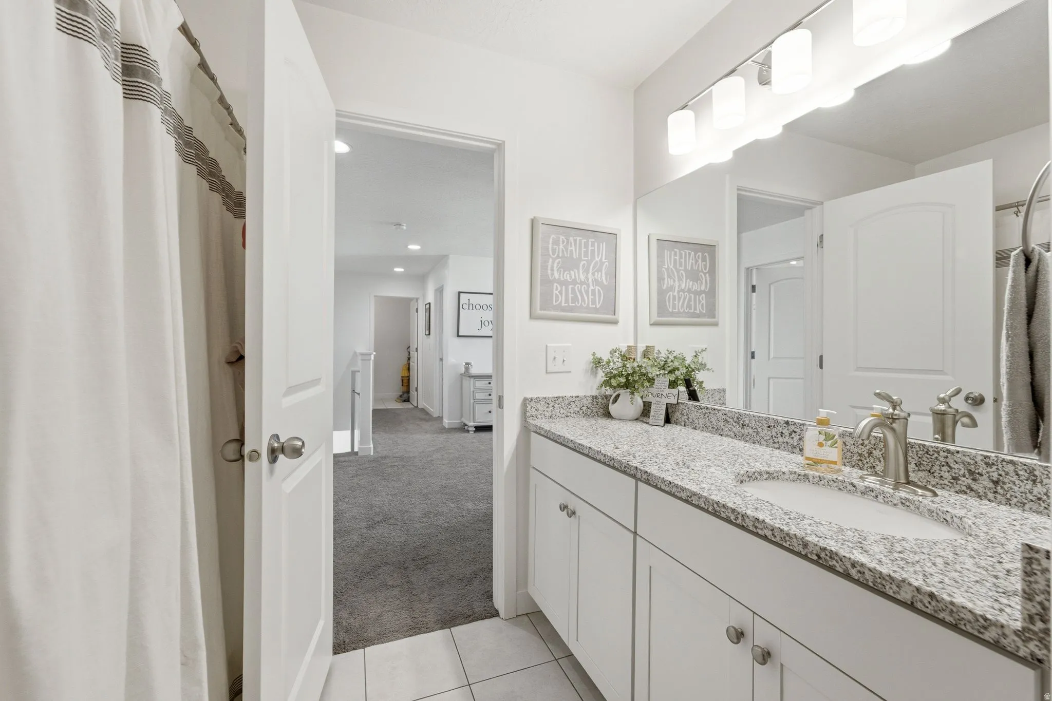 Bathroom featuring a double vanity with granite countertop, integrated sinks, and brushed nickel fixtures