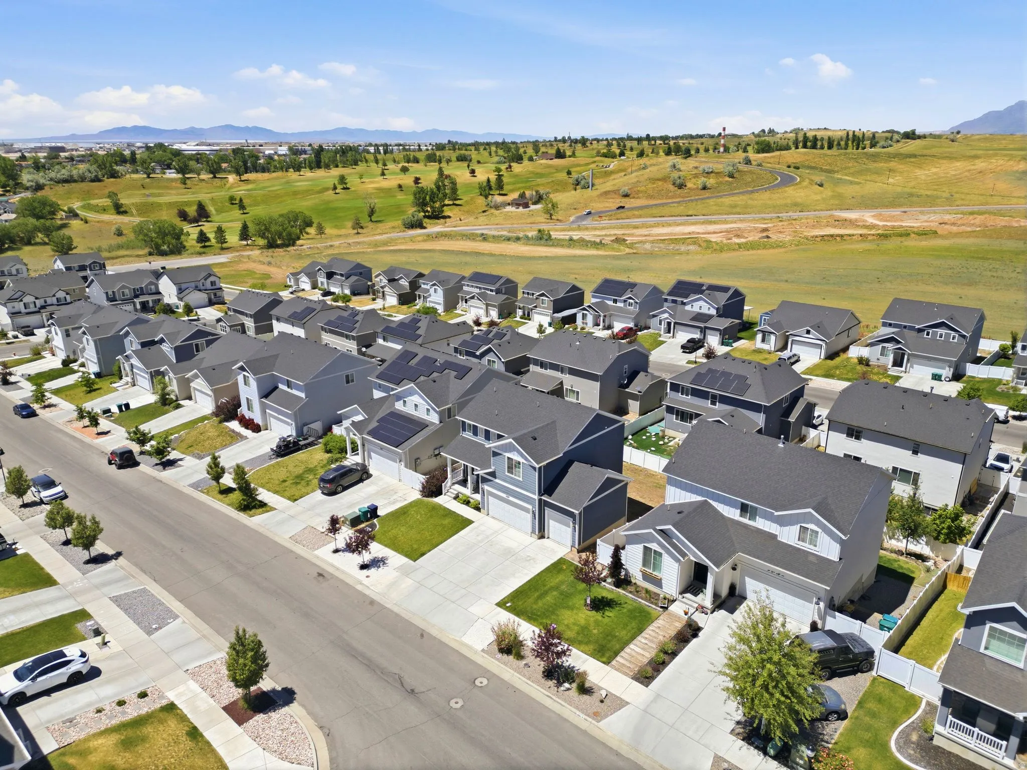Aerial view showcasing a residential neighborhood with detached homes featuring asphalt shingle roofs, some equipped with solar panels