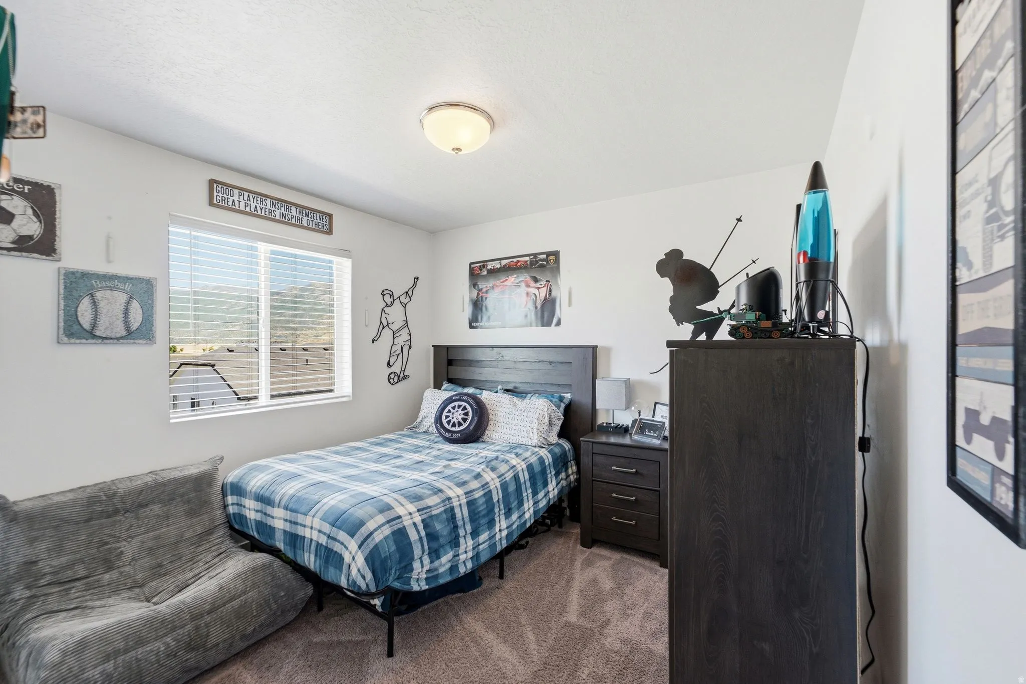 Bright bedroom featuring a single window with horizontal blinds, neutral wall paint, and a built-in ceiling light fixture