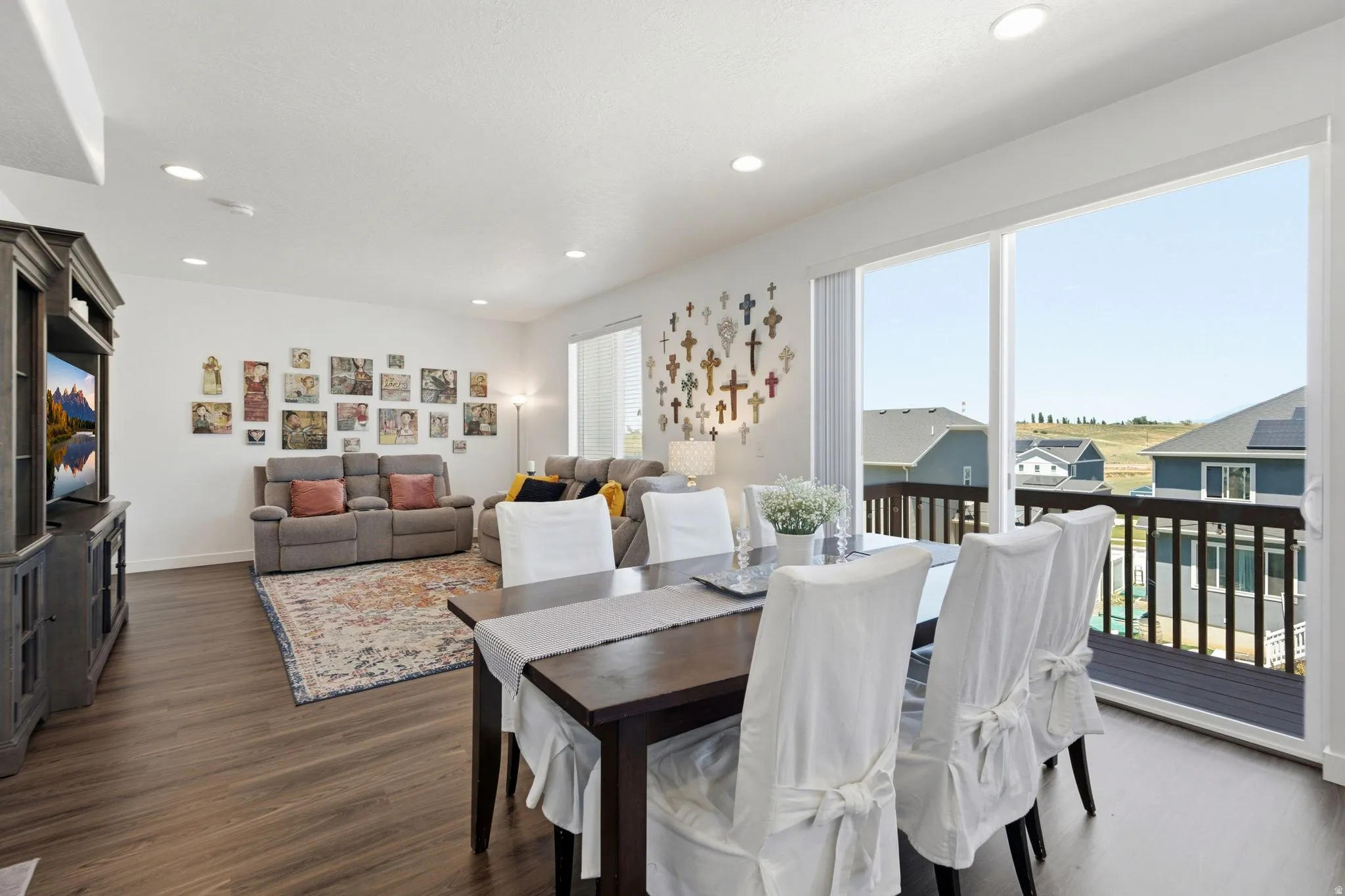 Open-concept living and dining area featuring wood-finish flooring, recessed lighting, and a sliding glass door opening to an outdoor deck