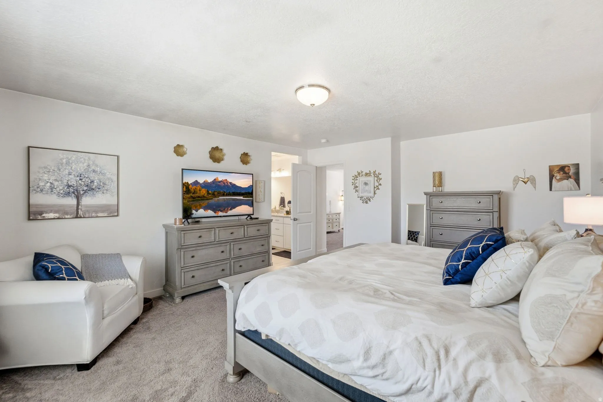 Carpeted bedroom with white walls, a semi-flush mount ceiling light fixture, and a doorway leading to an adjoining bathroom