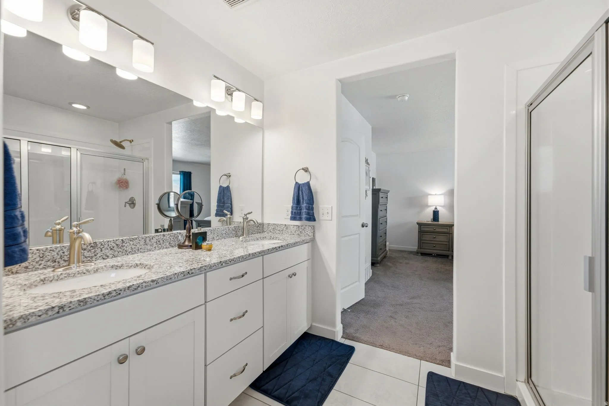 Bathroom featuring a dual vanity with a speckled countertop, white cabinetry, and brushed nickel hardware