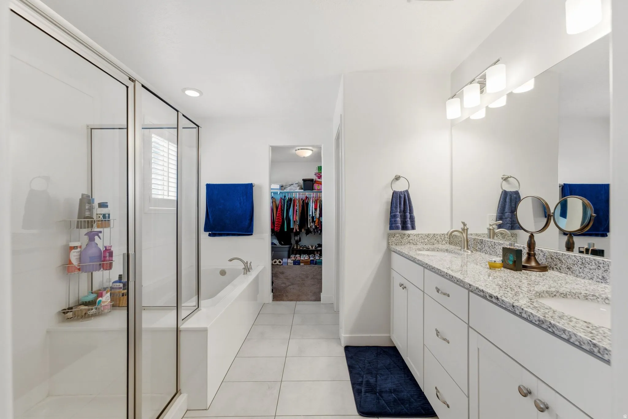 Bathroom featuring a dual vanity with light-toned countertops, and separate soaker tub with walk-in shower