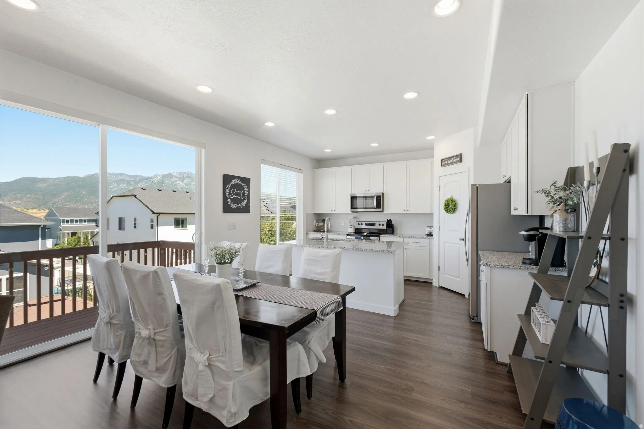 Open-concept dining and kitchen area featuring wood-finish flooring, recessed lighting, and a sliding glass door to an outdoor deck