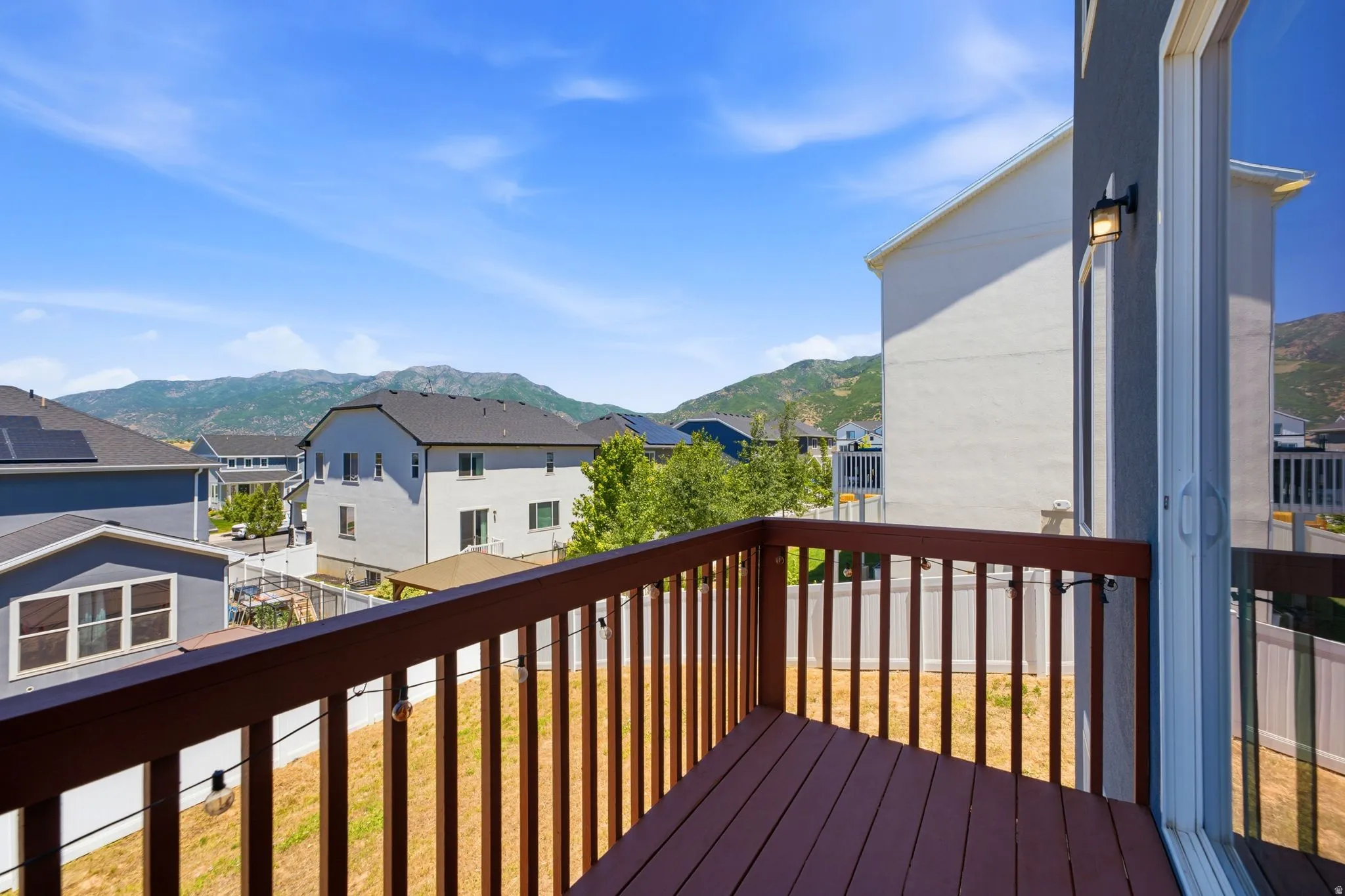Wood-tone balcony with a full railing and mountain scenery