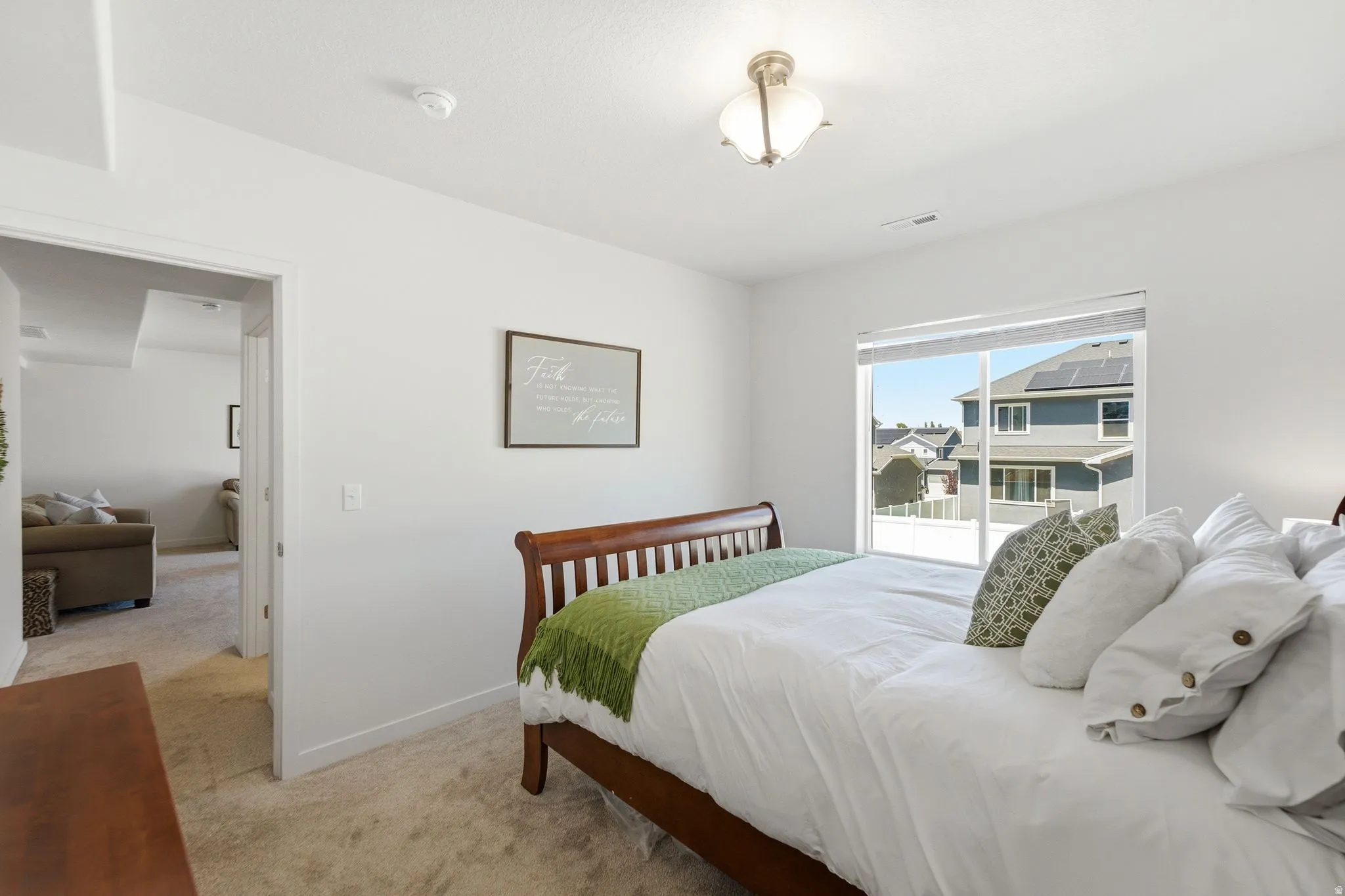 Spacious room featuring neutral carpeting, white walls, and a large window with white blinds