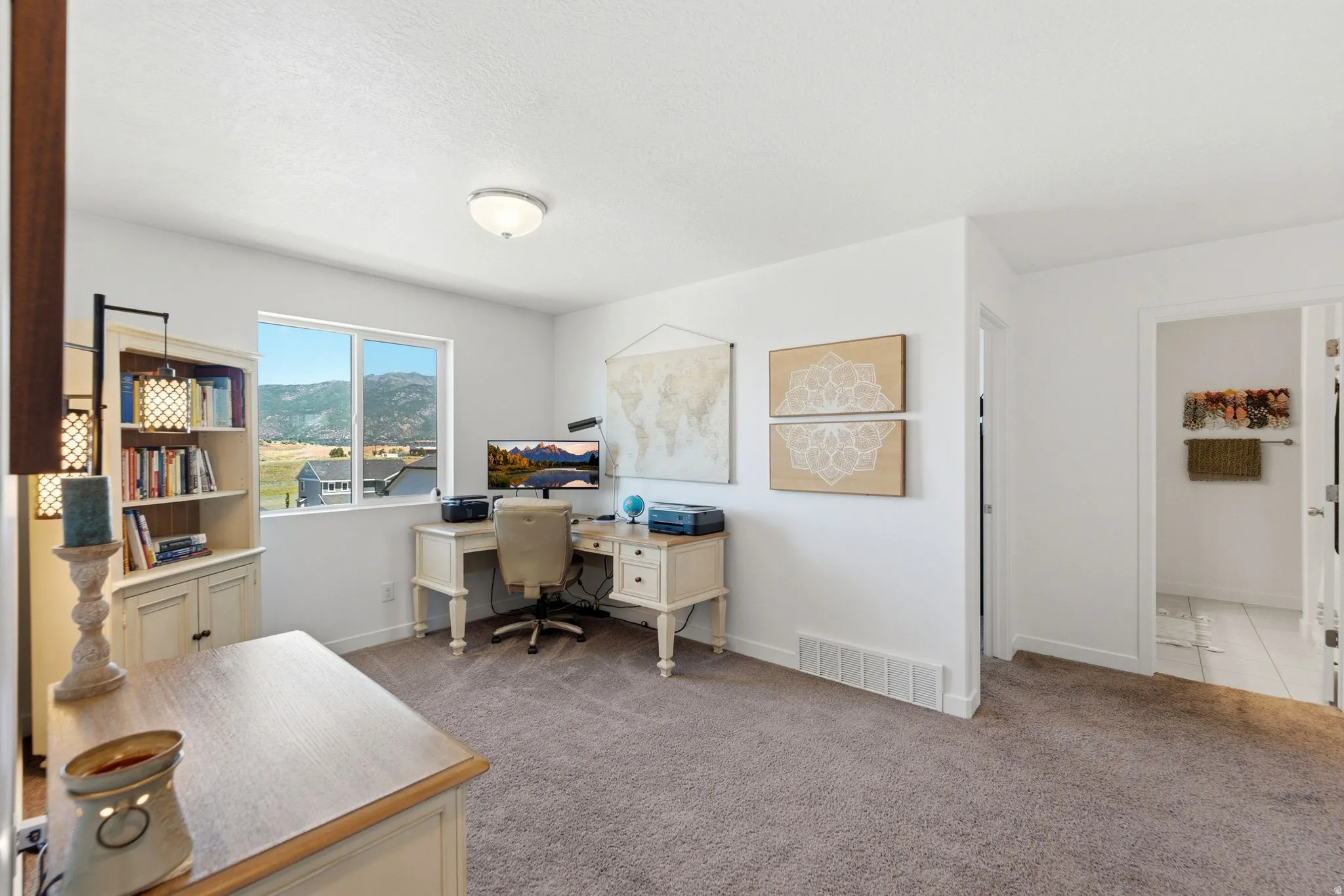 Spacious interior room with carpet flooring and ample natural light from a window with mountain and landscape scenery