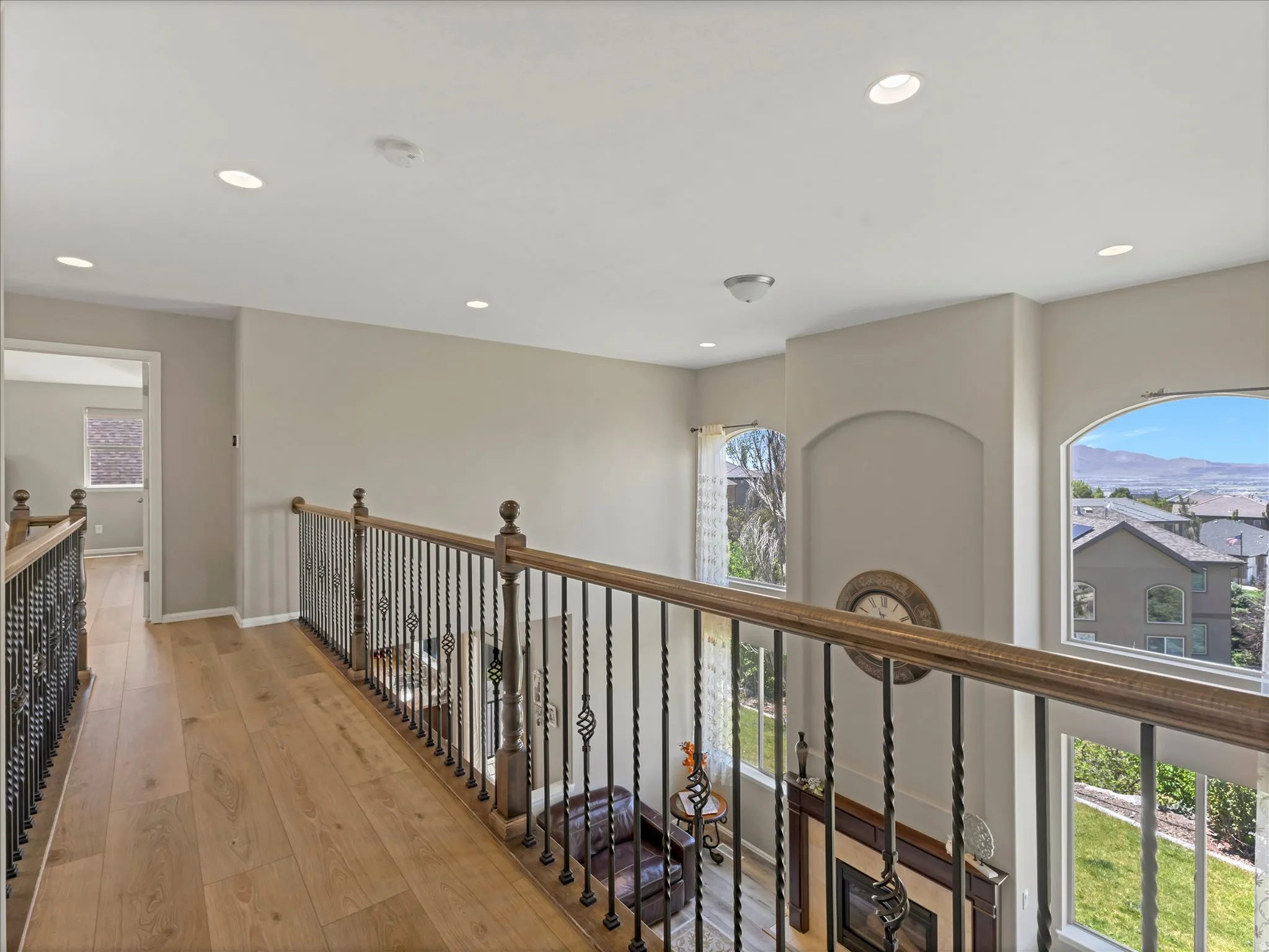 Open-concept upper-level landing featuring wood-finish flooring, recessed lighting, and black wrought iron railings with wood handrails