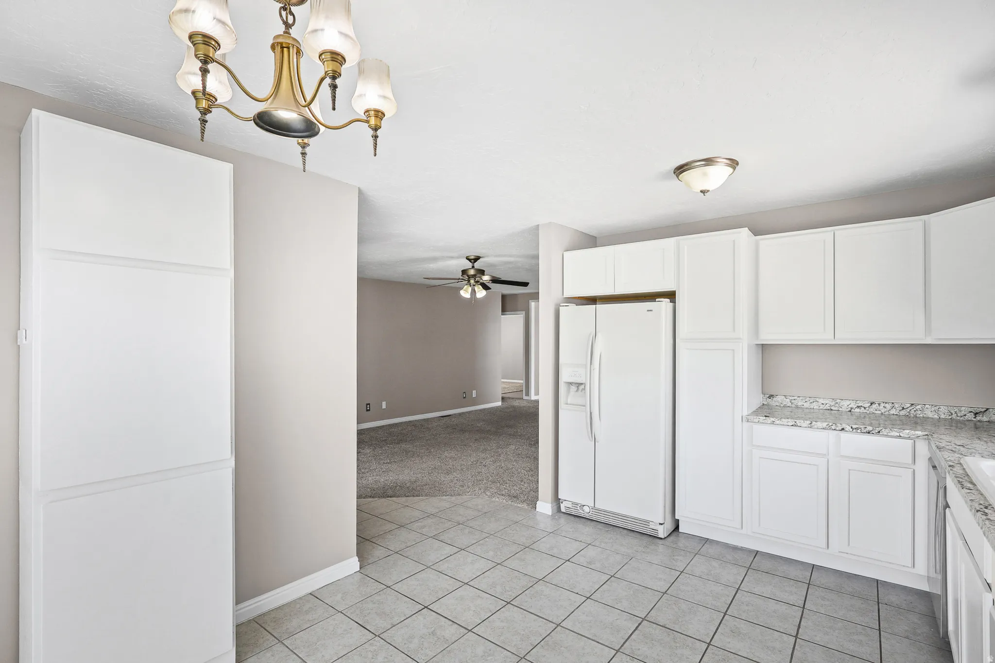 Kitchen featuring white cabinetry, light-toned tiled flooring, and a stone-finish countertop