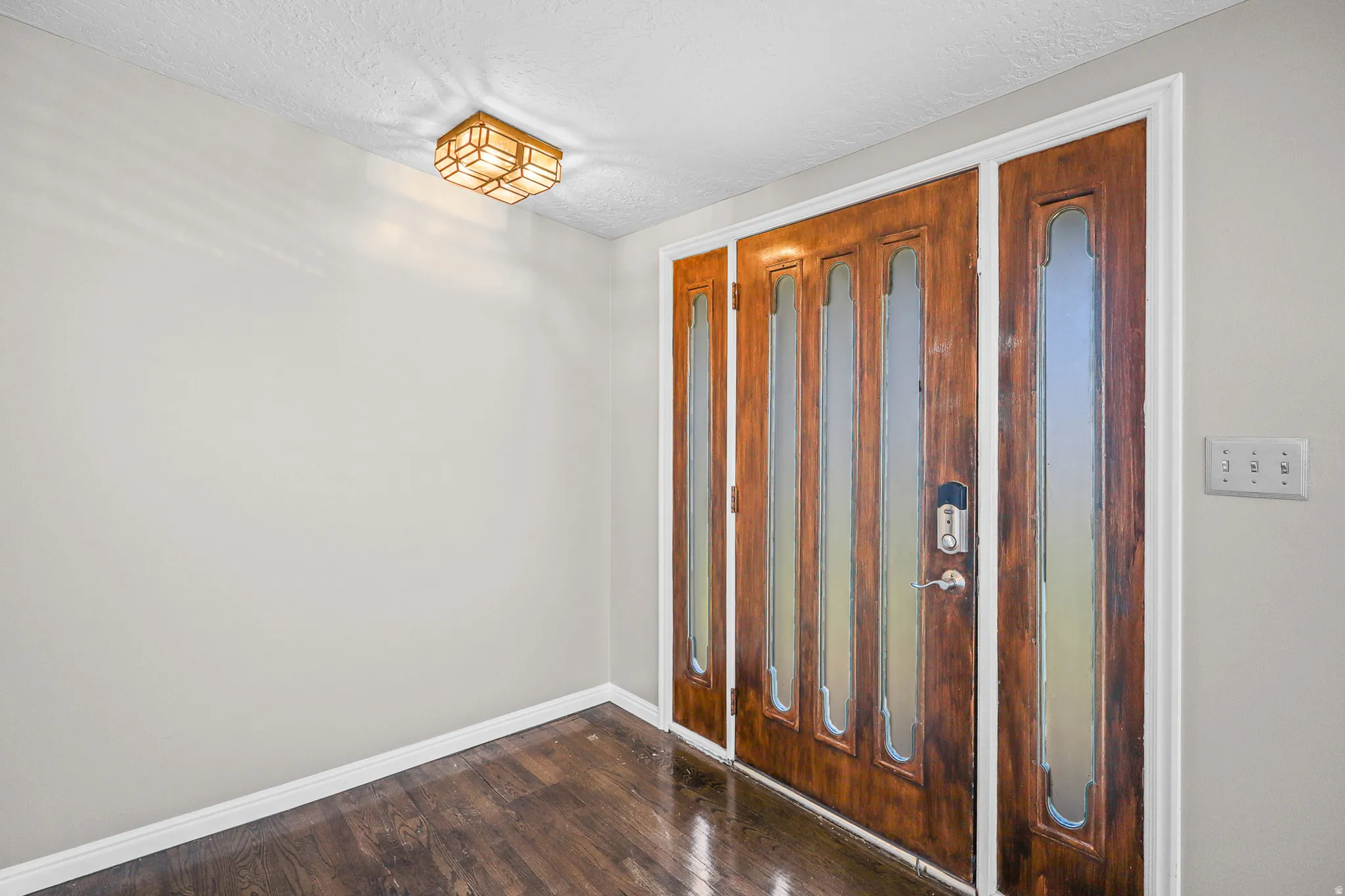 Rich wood-finish entry door with multiple glass inserts and sidelights