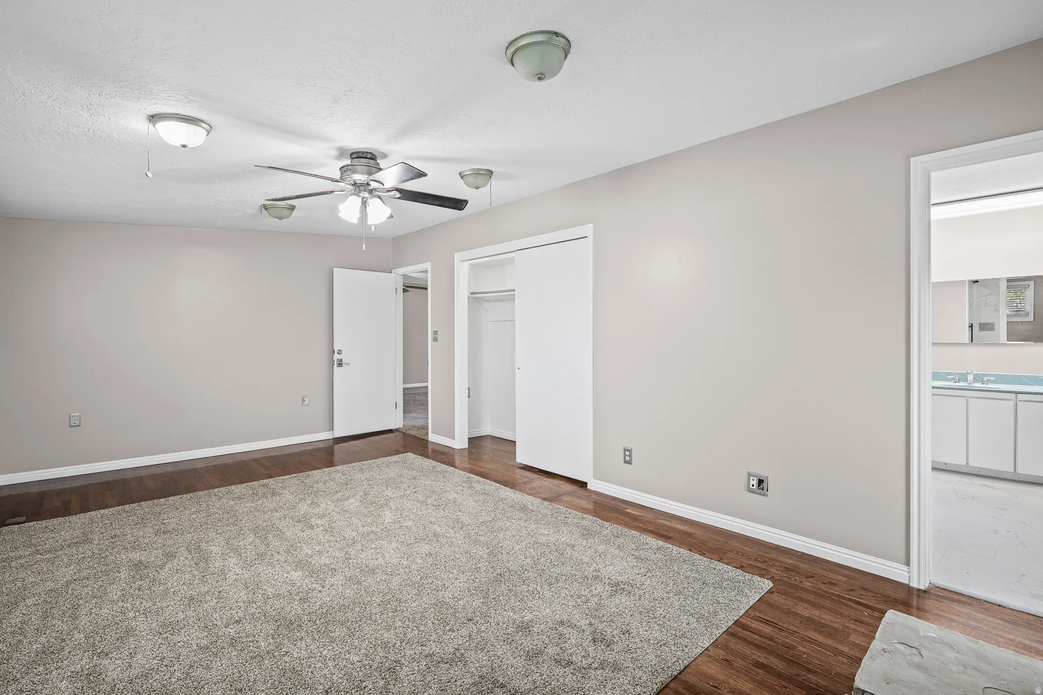 Room featuring wood-finish flooring, a ceiling fan with integrated lighting, and multiple recessed light fixtures