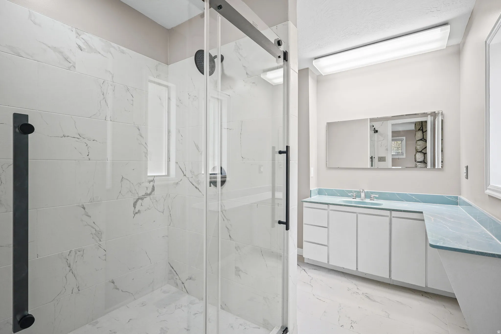 Walk-in shower with a frameless glass enclosure and black hardware