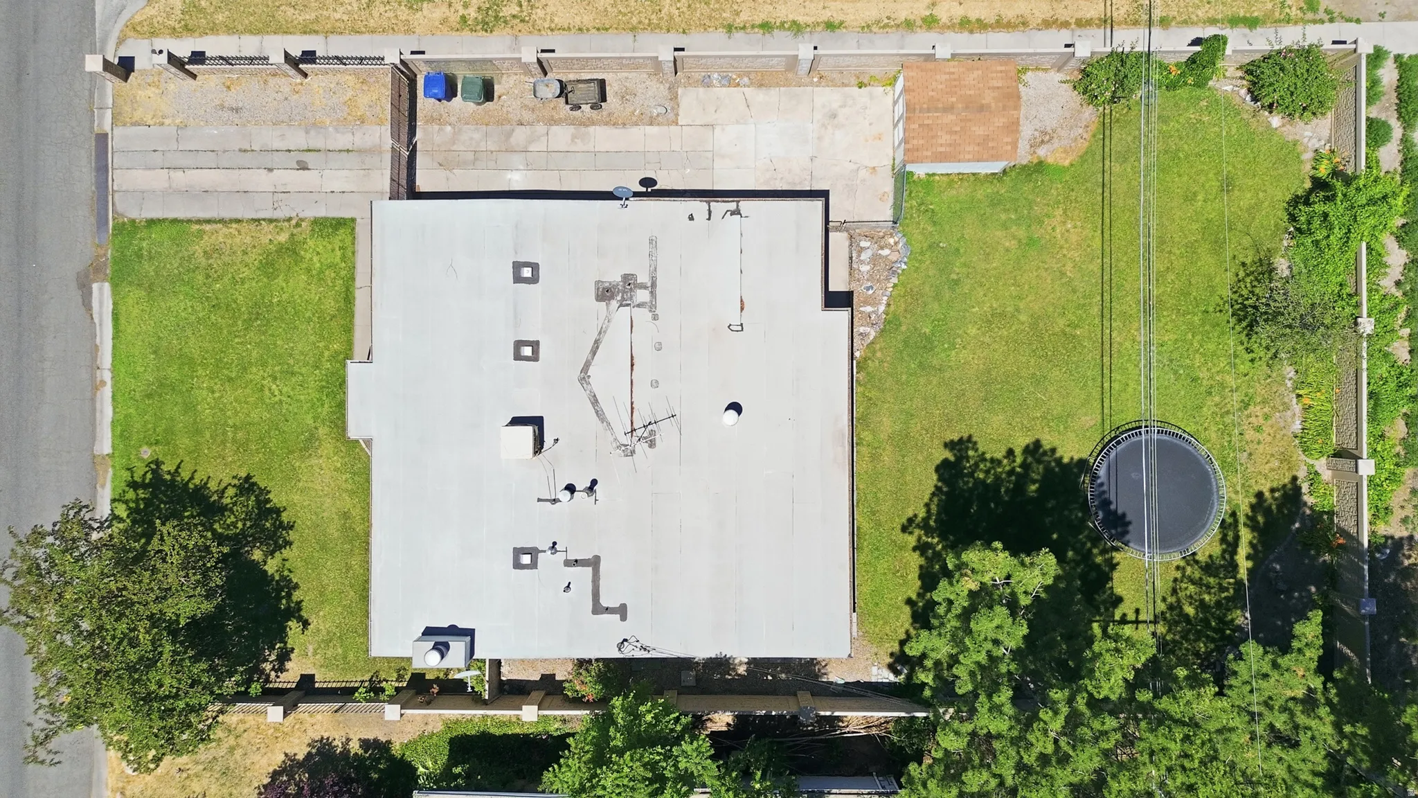 Expansive property featuring a large flat roof structure, concrete driveway, and a substantial grassy area