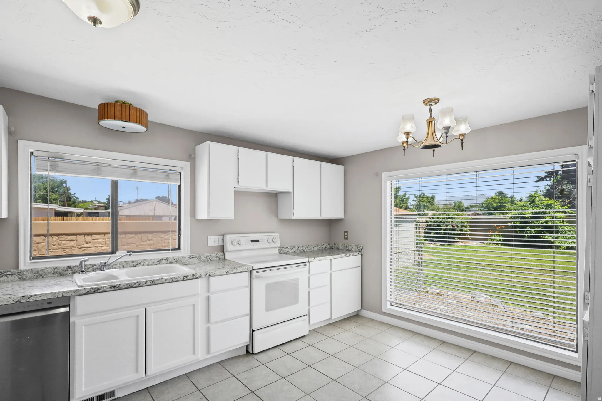 Kitchen featuring white cabinetry, dual-basin sink, and a four-burner electric range