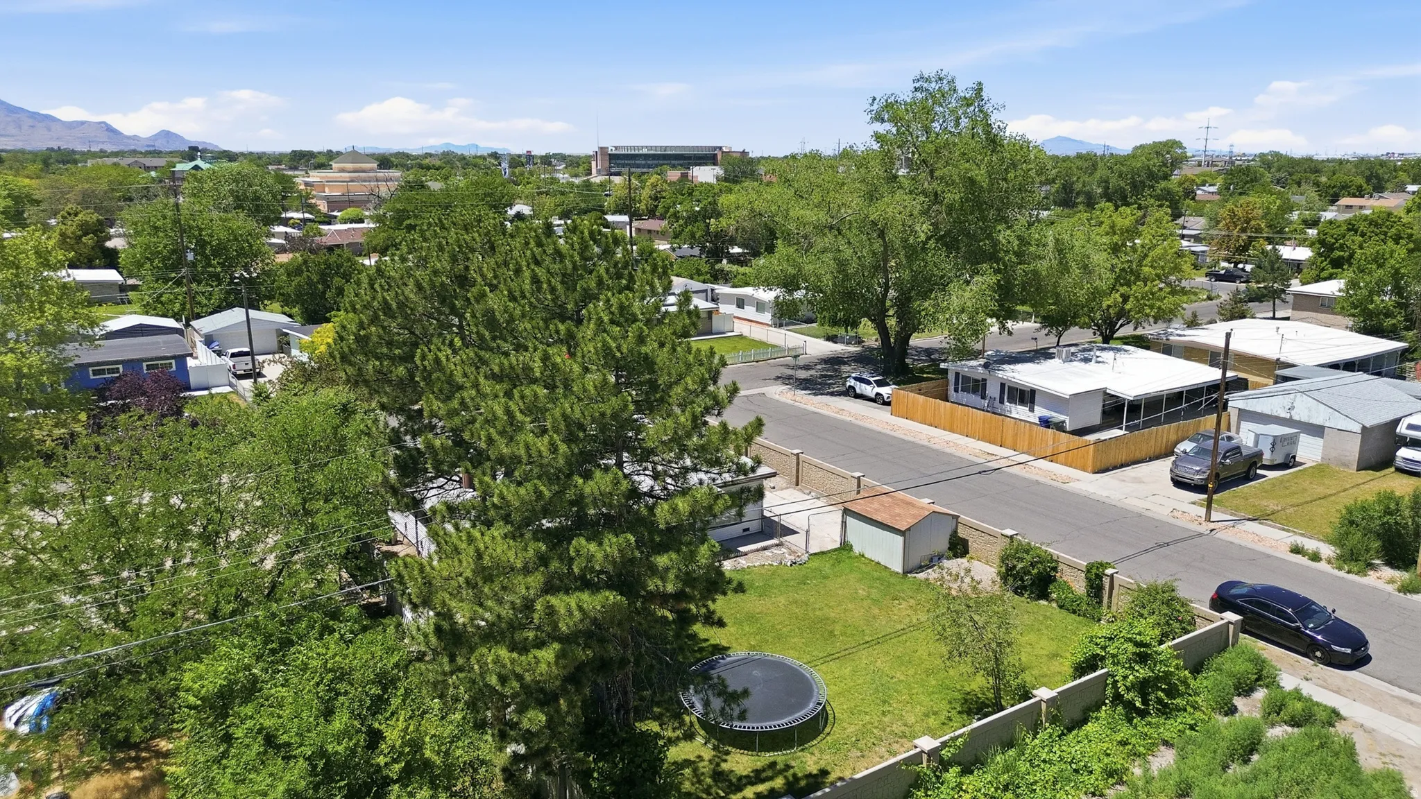 Mature trees and green landscaping frame this property, featuring a spacious grassy yard