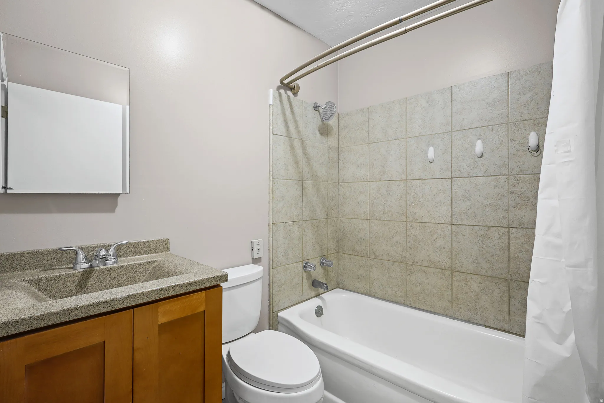 Bathroom featuring a light-toned vanity with an integrated sink and chrome faucet, a rectangular medicine cabinet, and a white toilet