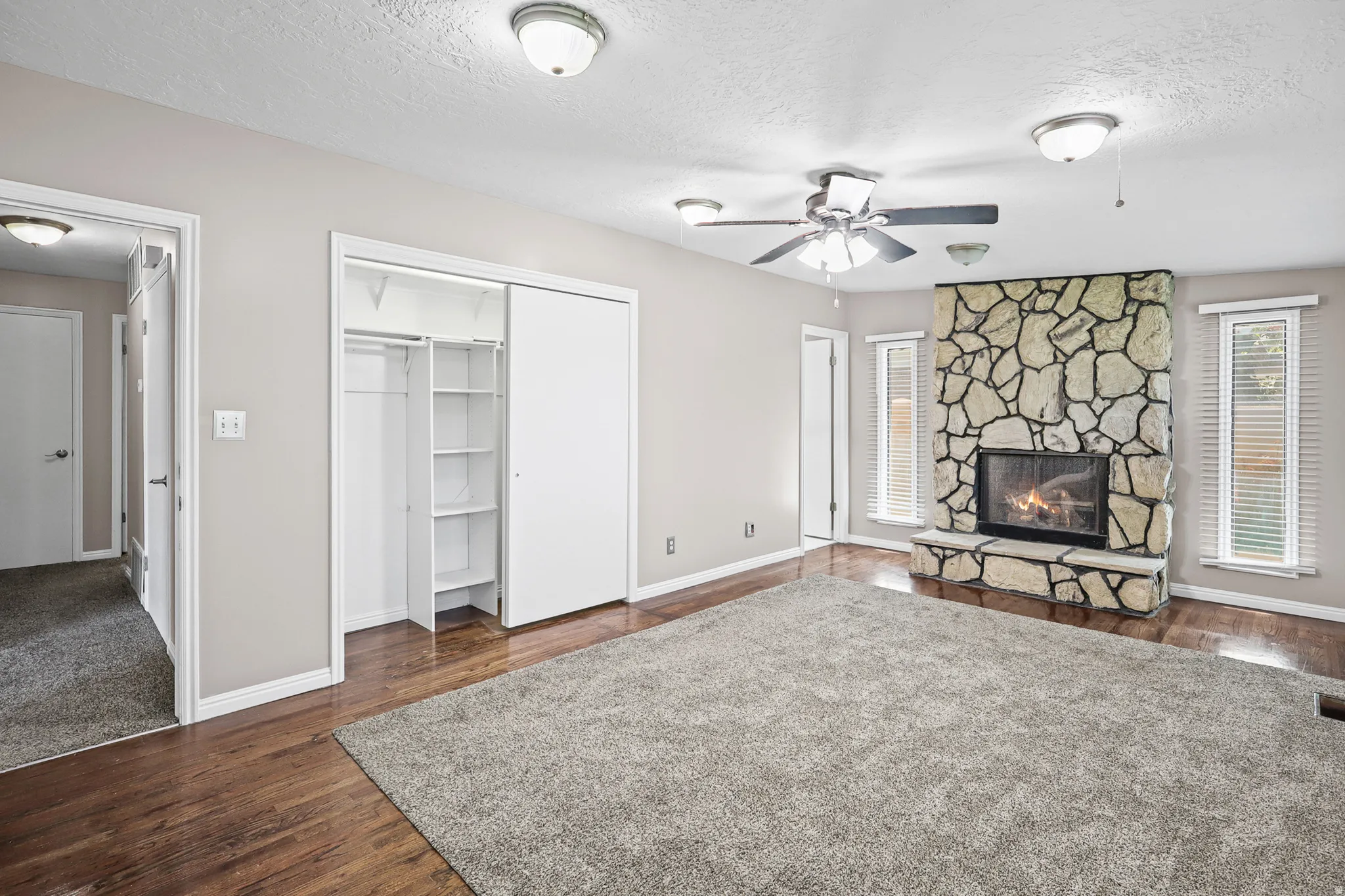 Spacious living area featuring a stone-clad fireplace and wood-finish flooring