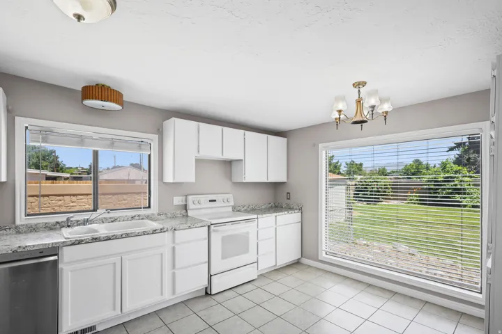 Kitchen featuring white cabinetry, dual-basin sink, and a four-burner electric range