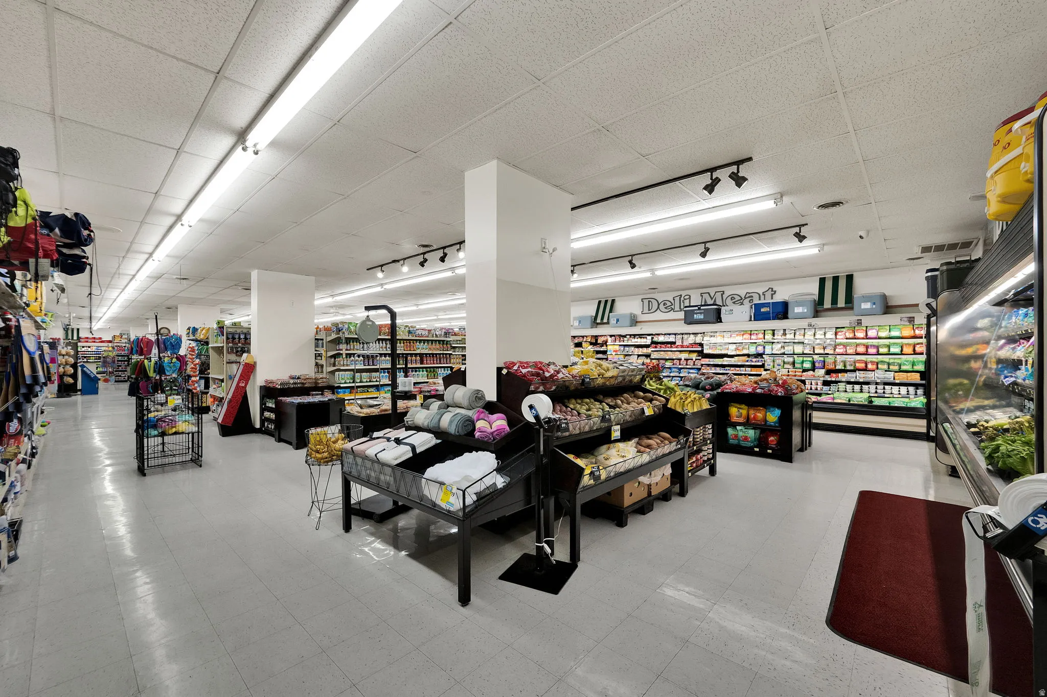 Expansive retail space featuring fluorescent overhead lighting, track lighting, and a suspended ceiling
